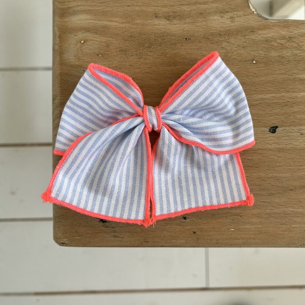La barrette à gros nœud Brunette bicolore rayures bleues et rose fluo